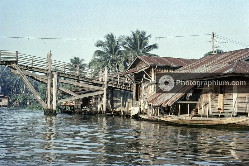 Riverside houses and a wooden bridge. Cambodia. 1976